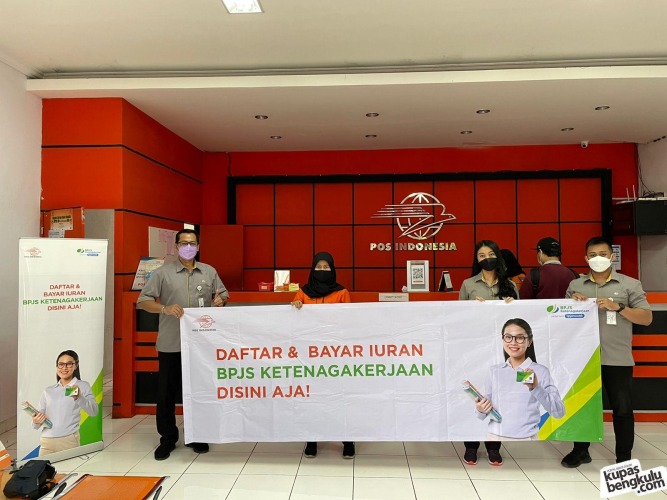 Pegawai BPJamsostek dan PT. Pos Indonesia saat membentangkan backdrop “Daftar dan Bayar Iuran BPJS Ketenagakerjaan Disini Aja” di kantor Pos Cabang Bengkulu, Rabu, 22 Desember 2021. Foto/Dok