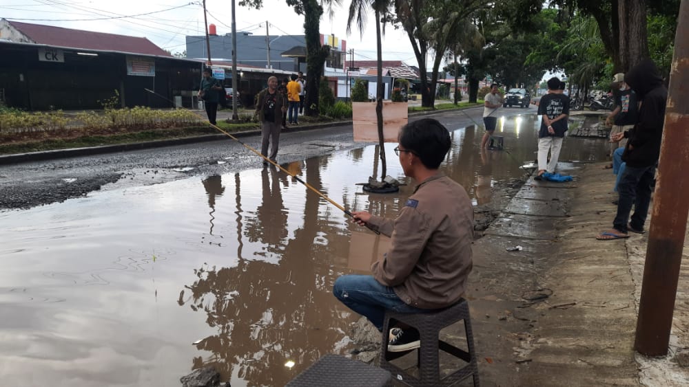 Seorang Mahasiswa tampak sedang melakukan aksi memancing di kubangan Jalan Hibrida Kota Bengkulu, Selasa, 13 Desember 2022, Foto: Dok